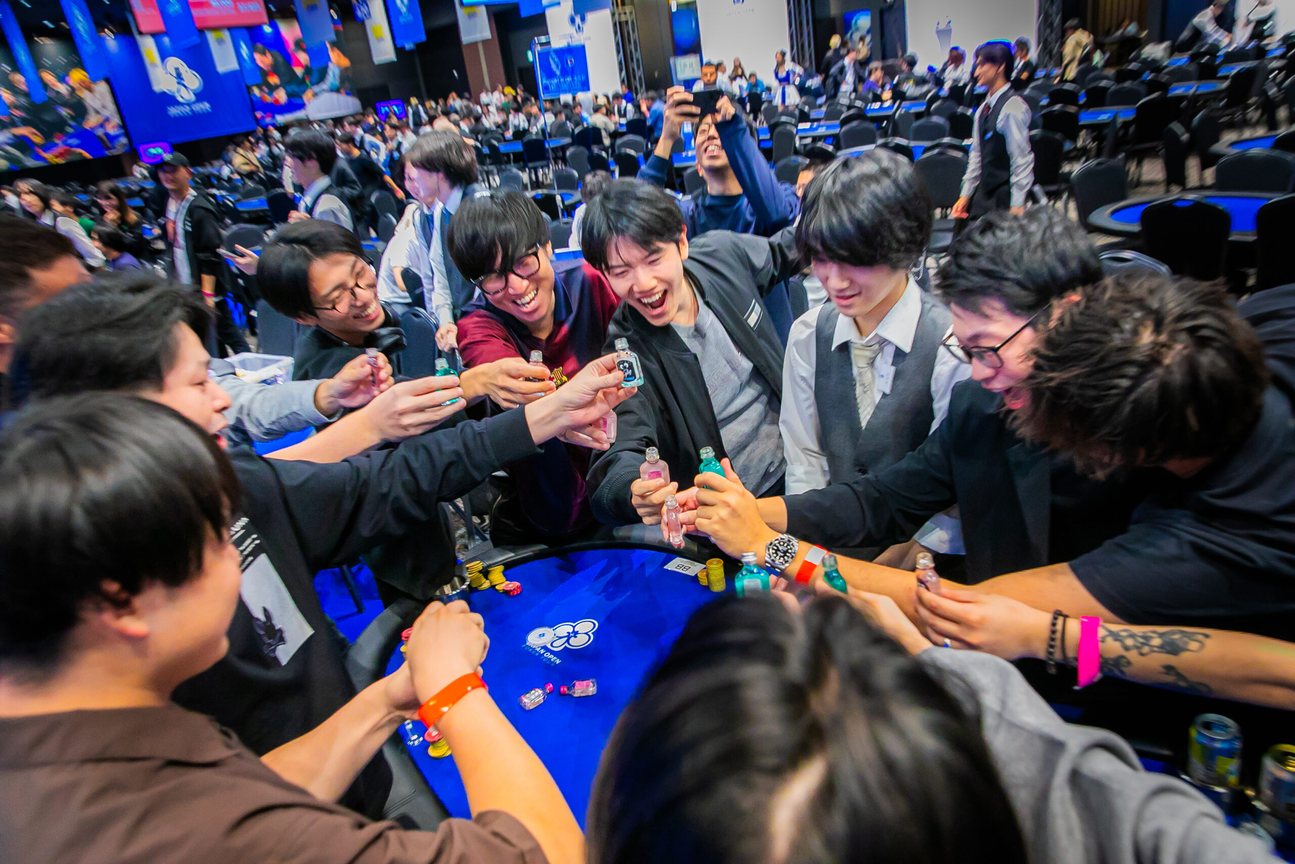 プレイヤーがポーカーテーブルを囲んで乾杯する様子